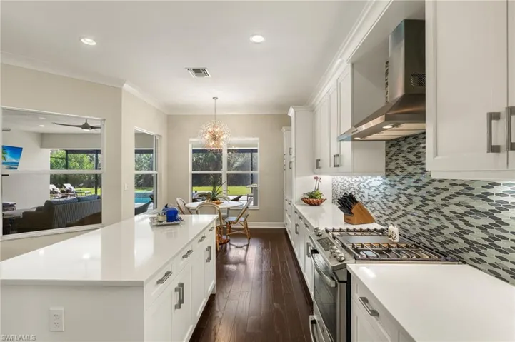 Kitchen with wall chimney exhaust hood, dark hardwood / wood-style floors, a center island, high end stainless steel range, and decorative backsplash