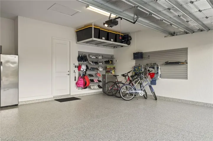 Garage featuring stainless steel refrigerator and a garage door opener
