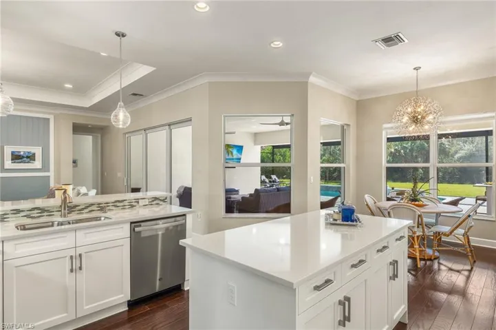 Kitchen featuring white cabinets, stainless steel dishwasher, decorative light fixtures, and dark hardwood / wood-style floors