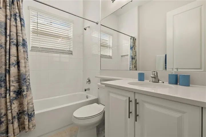 Full bathroom with toilet, vanity, tile patterned floors, and shower / bathtub combination with curtain