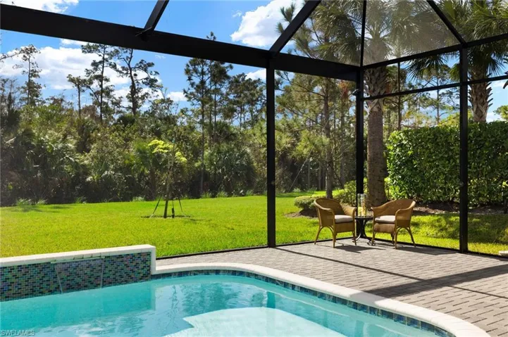 View of pool featuring a yard, glass enclosure, and a patio area