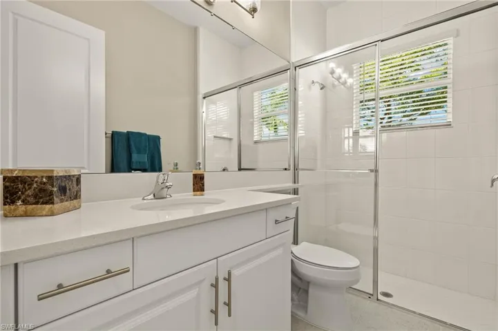 Bathroom featuring walk in shower, vanity, and a wealth of natural light