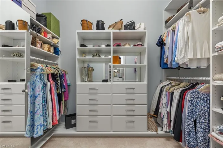 Custom 1st walk in closet featuring light carpet
