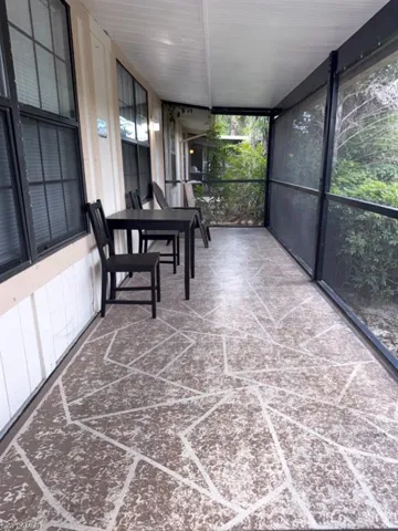 Screened porch featuring a geometrically patterned concrete floor, white tongue-and-groove ceiling, and exterior wall paneling with multiple windows