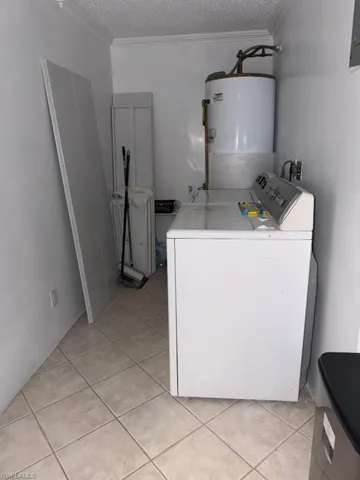 Laundry area featuring a top-load washing machine, a water heater, and light-toned tile flooring