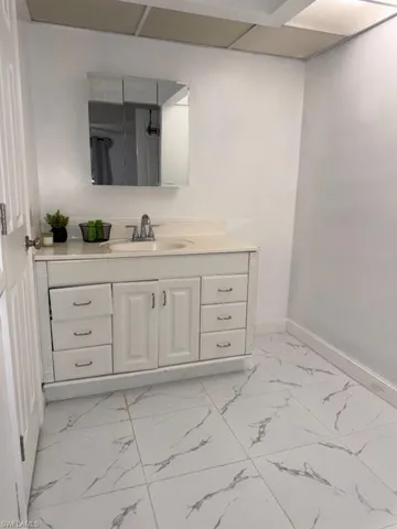 Bathroom vanity featuring a white cabinet with multiple drawers and a central double-door storage