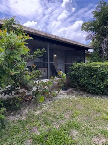 Screened patio with a covered overhang, surrounded by mature landscaping and a grassy area