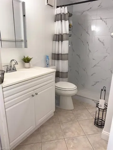 Bathroom featuring a white vanity with integrated sink, chrome faucet, and mirrored medicine cabinet