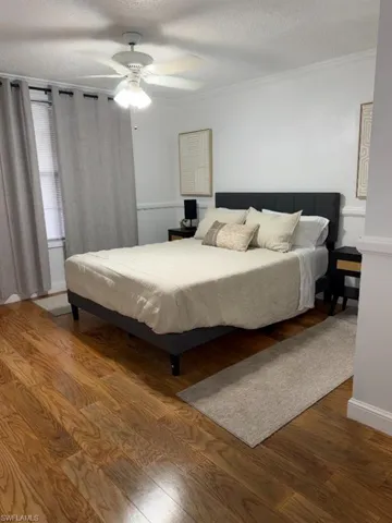 Spacious room featuring wood-finish flooring, white walls, and a ceiling fan with integrated lighting