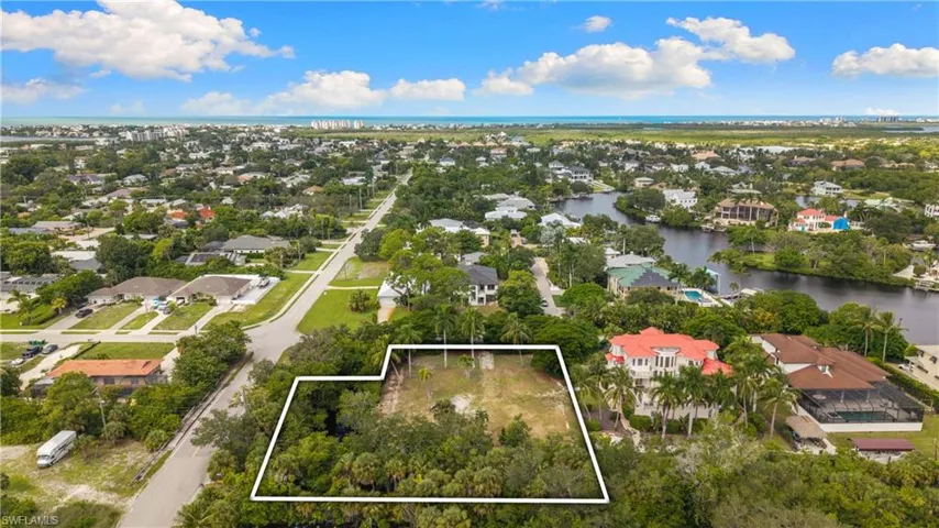 Cleared building lot with mature trees and a distant water horizon