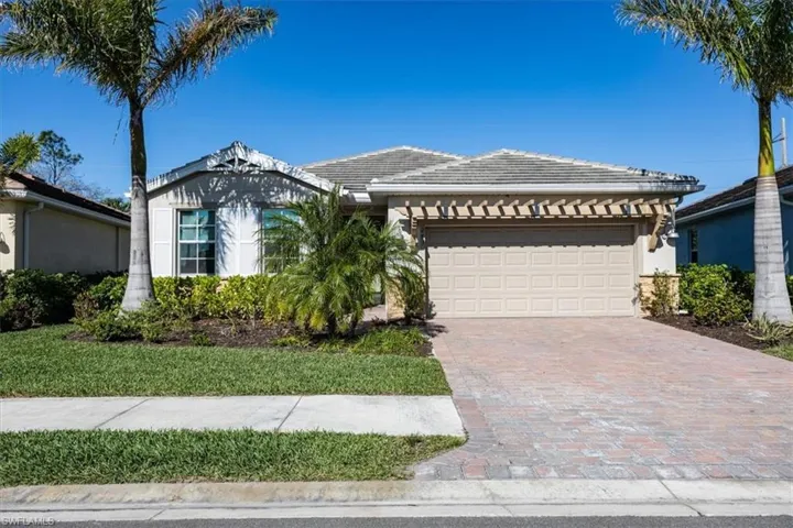 Single story home featuring a tiled roof, an attached garage, and decorative driveway