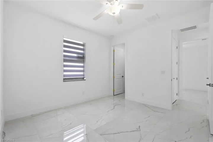 Unfurnished bedroom with light marble finish floors and ceiling fan