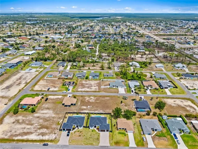 Aerial view of property and surrounding area featuring nearby suburban area
