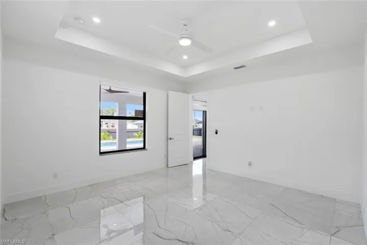 Spare room with a tray ceiling, light marble finish flooring, ceiling fan, and recessed lighting