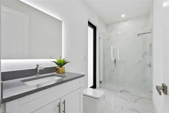 Full bath with vanity, a marble finish shower, light marble finish floors, and recessed lighting