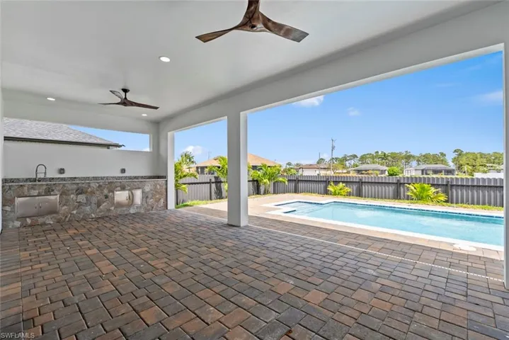 View of swimming pool featuring ceiling fan, a fenced backyard, a patio, and exterior kitchen