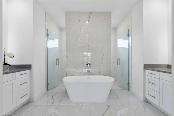Bathroom with plenty of natural light, vanity, a soaking tub, and a marble finish shower