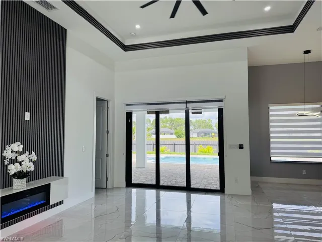 Unfurnished room with light marble finish flooring, a raised ceiling, recessed lighting, ceiling fan, and ornamental molding