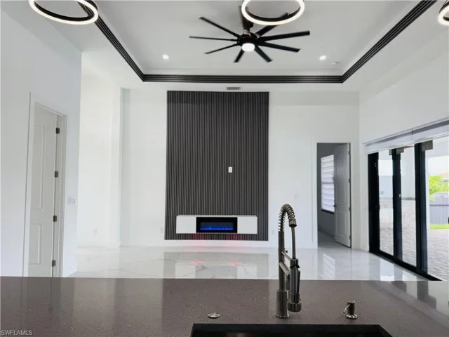 Kitchen featuring a glass covered fireplace, dark stone counters, and ceiling fan