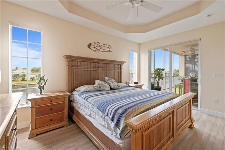 Bedroom featuring ceiling fan, light hardwood / wood-style flooring, a raised ceiling, and access to outside