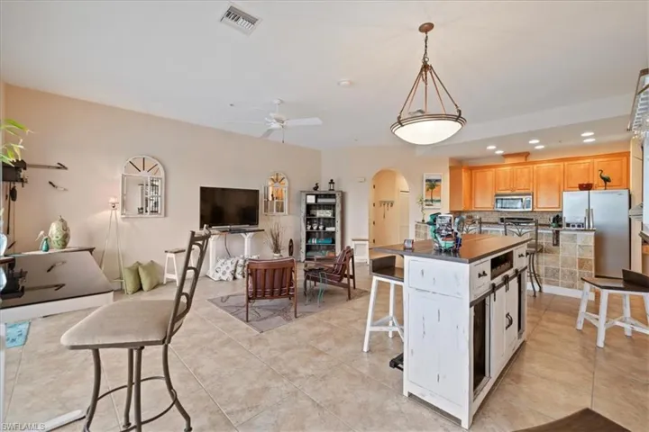 Kitchen with stainless steel appliances, backsplash, decorative light fixtures, light tile patterned flooring, and a kitchen island