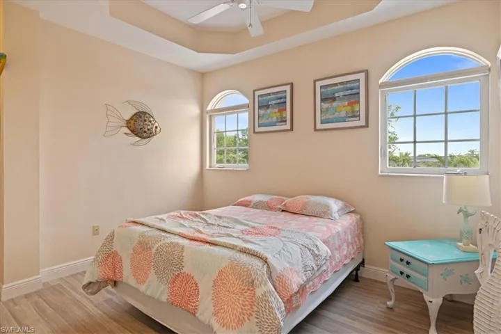 Bedroom with ceiling fan, hardwood / wood-style flooring, and a raised ceiling