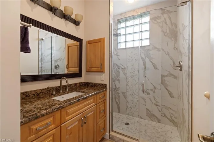 Bathroom featuring a shower with shower door and vanity