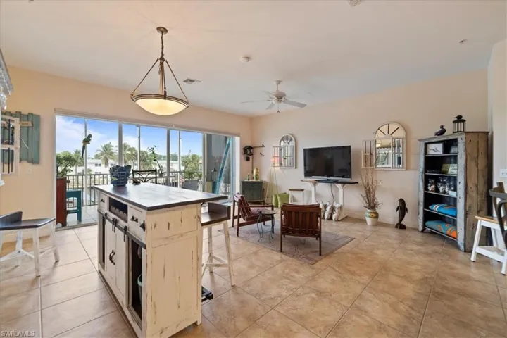 Kitchen featuring ceiling fan, light tile patterned flooring, hanging light fixtures, and a center island