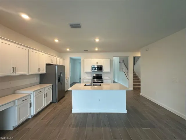 Kitchen with dark wood-type flooring, white cabinets, and stainless steel appliances