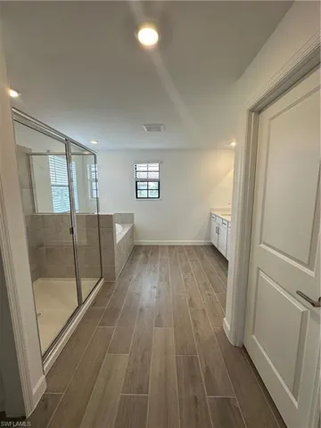 Bathroom with hardwood / wood-style flooring, shower with separate bathtub, and vanity