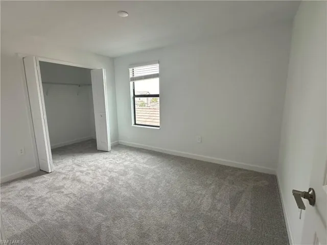 Unfurnished bedroom featuring light carpet and a closet