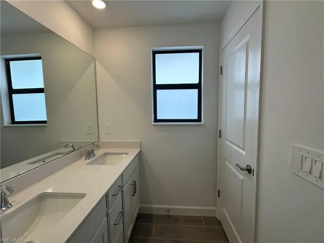 Bathroom featuring tile patterned flooring, a healthy amount of sunlight, and dual bowl vanity