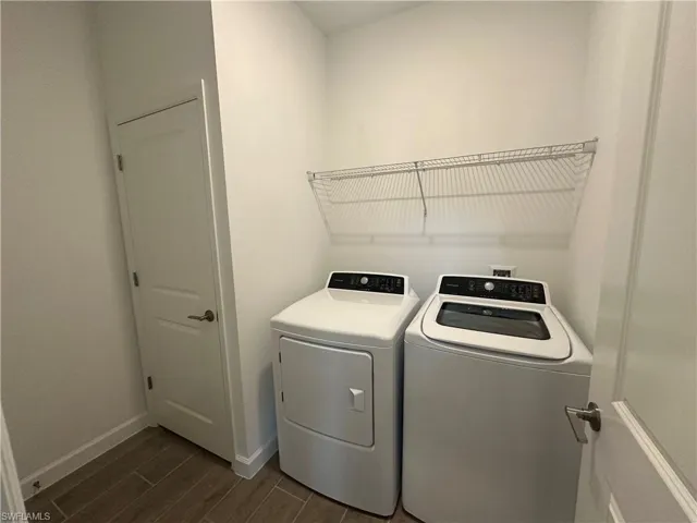 Laundry room with dark hardwood / wood-style floors and washing machine and clothes dryer