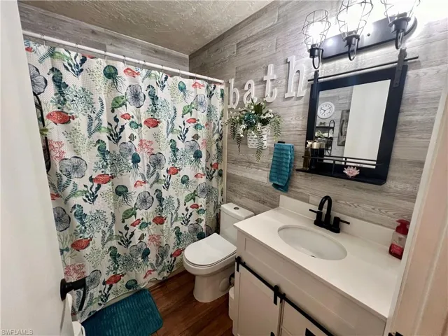 Bathroom with luxury vinyl plank walls and floors, vanity, and toilet
