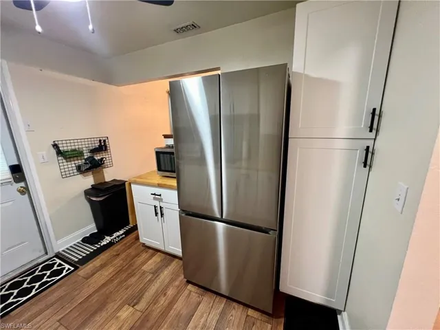 Kitchen with ceiling fan, wooden counters, white cabinetry, stainless steel appliances, and luxury vinyl plank flooring.