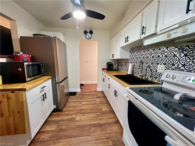 Kitchen with luxury vinyl plank flooring,  wood counters, white cabinets and ceiling fan