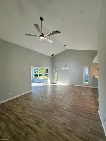 Unfurnished living room featuring a high ceiling, dark wood-type flooring, and silver ceiling fan