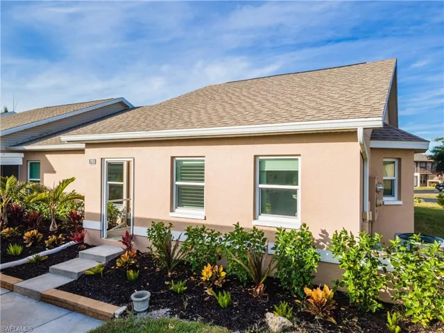 View of front of house featuring beautiful landscaping, roof with shingles and stucco siding