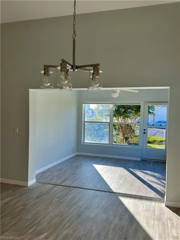 Unfurnished dining area with a high ceiling, wood finished floors, and new modern lighting