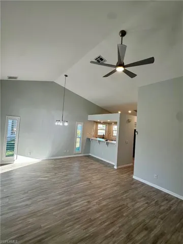Unfurnished living room, a high ceiling, and a new silver ceiling fan