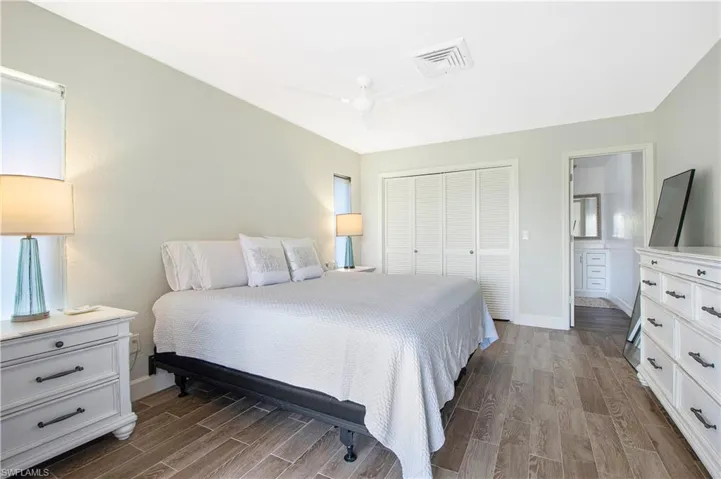Bedroom with hardwood / wood-style floors, a closet, ceiling fan, and ensuite bath