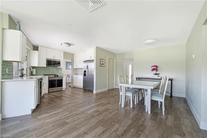 Kitchen featuring hardwood / wood-style floors, backsplash, sink, white cabinets, and appliances with stainless steel finishes