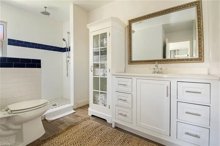 Bathroom with wood-type flooring, a tile shower, toilet, and vanity