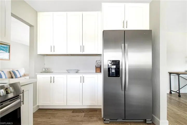 Kitchen featuring stainless steel fridge with ice dispenser, white cabinets, hardwood / wood-style flooring, and range