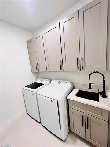 Laundry room featuring independent washer and dryer, cabinet space, and baseboards
