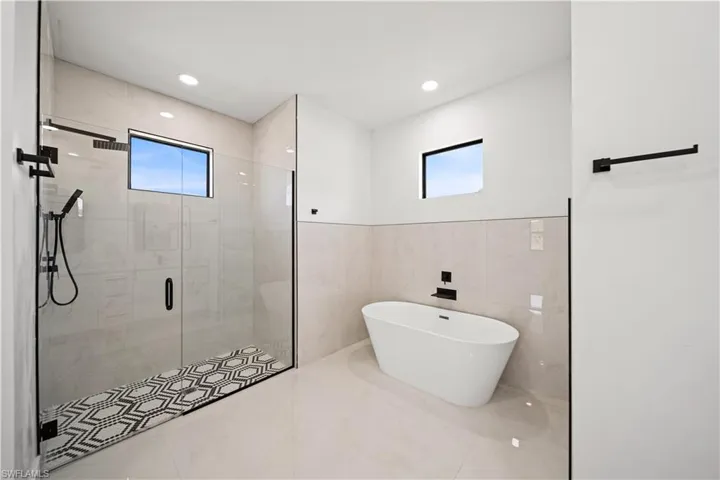 Bathroom with a stall shower, a freestanding tub, marble finish flooring, tile walls, and recessed lighting