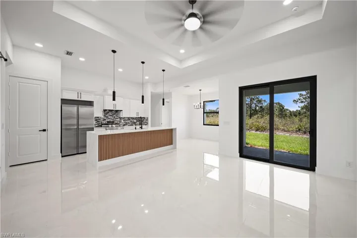 Kitchen with built in refrigerator, a ceiling fan, light countertops, recessed lighting, and a spacious island