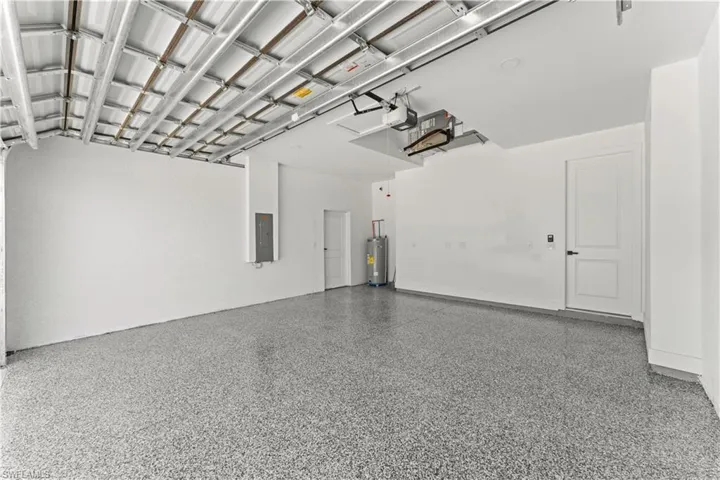 Garage with water heater, a garage door opener, and electric panel