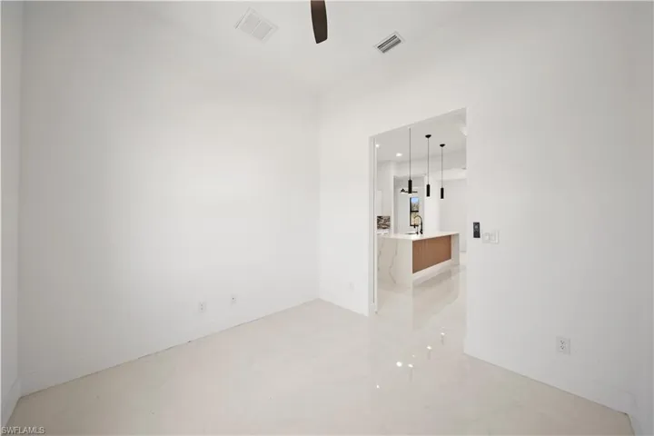 Unfurnished room featuring a ceiling fan, baseboards, and light marble finish floors