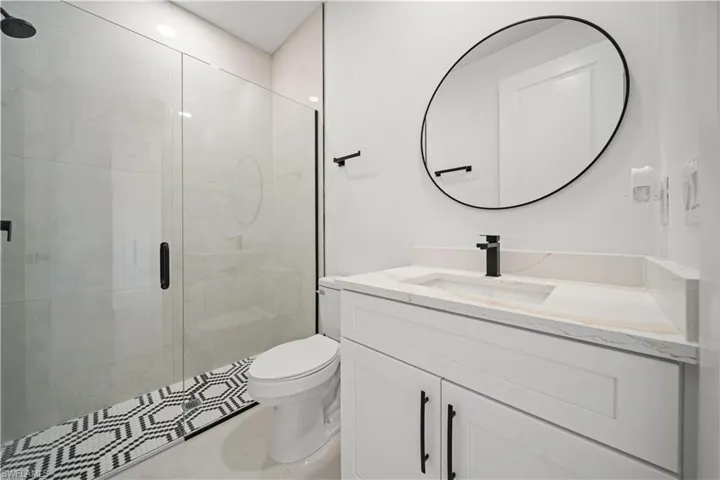 Bathroom featuring toilet, a stall shower, and vanity